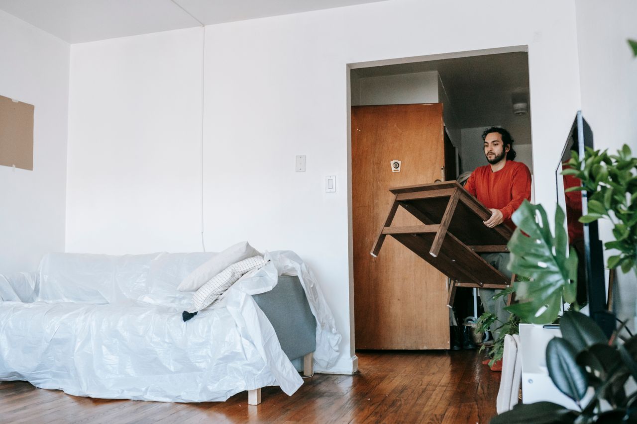 services-02 Man holding a wooden table during relocation in a contemporary apartment.