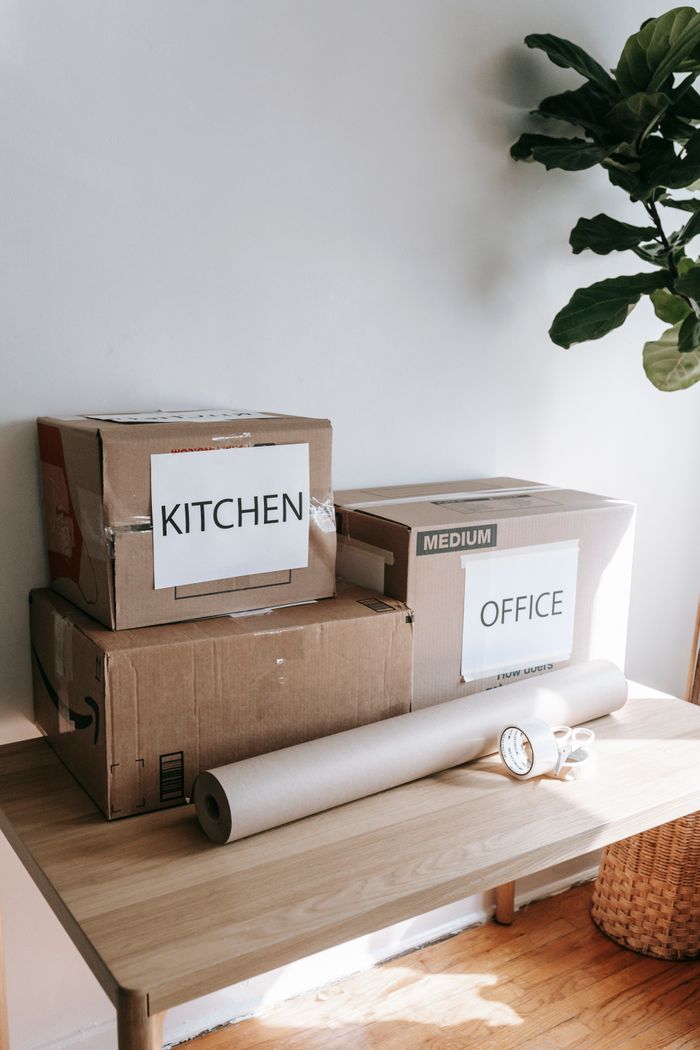 services-03 Cardboard boxes labeled for kitchen and office on a wooden table indicating moving day.